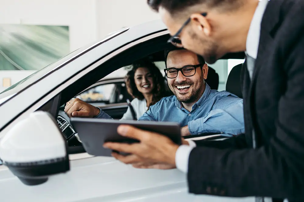 Automobilverkäufer zeigt einem Mann etwas auf einem Tablet